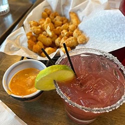 basket of cheese curds with dipping sauce and a pink mixed drink at Riff Raff