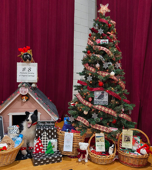 Our Festival of Trees decorated tree with dog house, and multiple baskets of gifts.